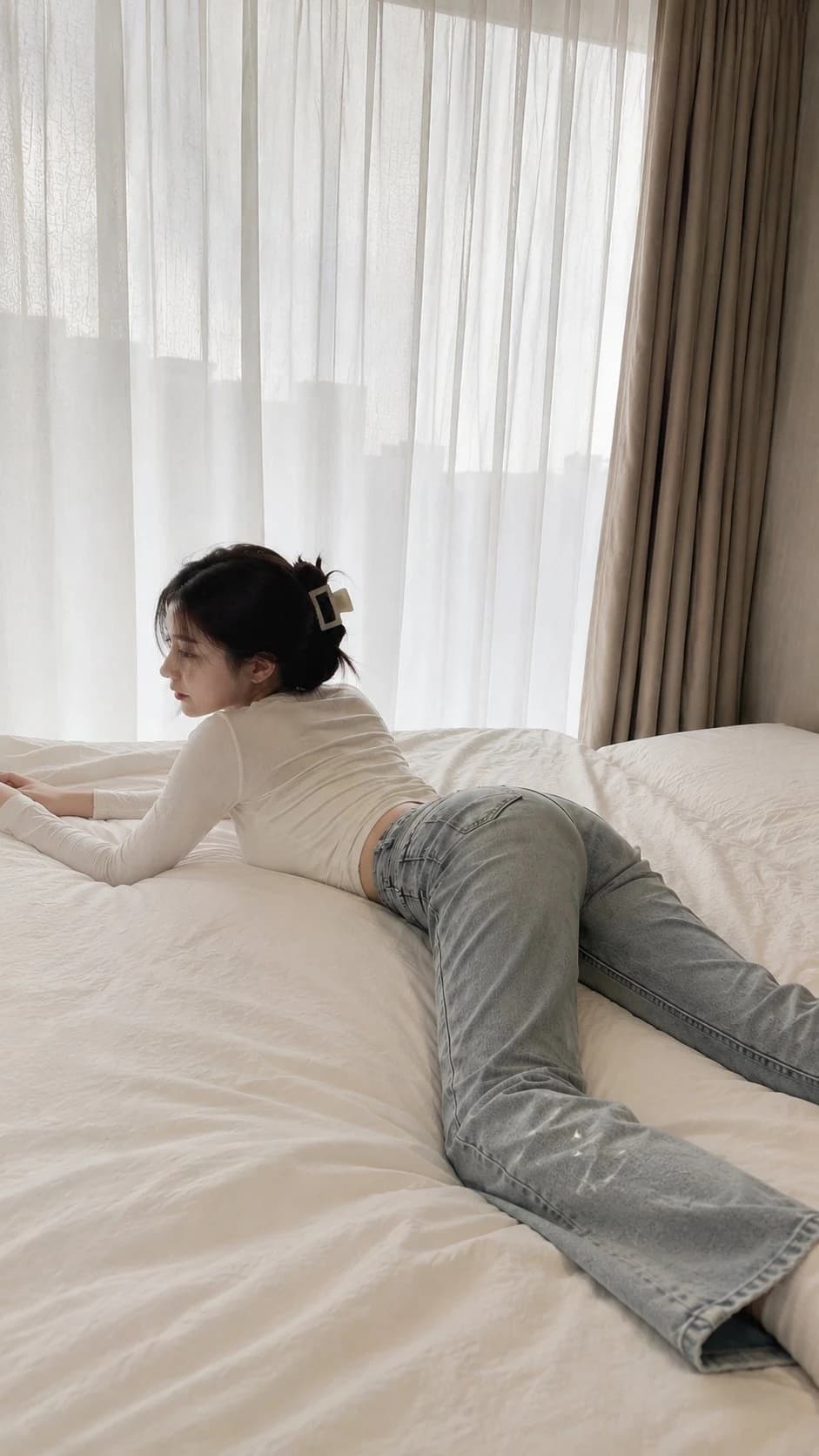 白衣女子趴在白色床铺上的自然光卧室写实照片